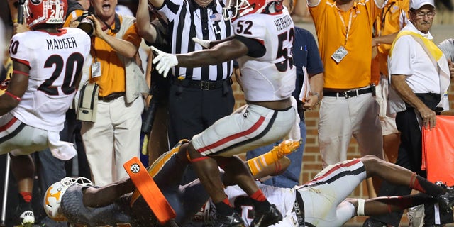 Tennessee's Alton Howard, bottom left, falls into the endzone after he fumbled the ball for a turnover as Georgia's Amarlo Herrera (52) contents the original call as a touchdown in overtime of an NCAA college football game in Knoxville, Tenn., Oct. 5, 2013. (AP Photo/Atlanta Journal-Constitution, Jason Getz)