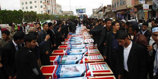 Mourners stand near the coffins of a men who were killed last Thursday by a suicide bomber in central Sanaa, Yemen, Tuesday, Oct. 14, 2014.  Two suicide bombings in Yemen killed nearly 70 people last Thursday, with one targeting an anti-government rally by followers of the Houthi Shiite group,  who control Sanaa.  (AP Photo/Hani Mohammed)