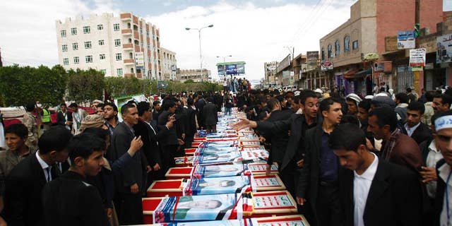 Mourners stand near the coffins of a men who were killed last Thursday by a suicide bomber in central Sanaa, Yemen, Tuesday, Oct. 14, 2014. Two suicide bombings in Yemen killed nearly 70 people last Thursday, with one targeting an anti-government rally by followers of the Houthi Shiite group, who control Sanaa. (AP Photo/Hani Mohammed)