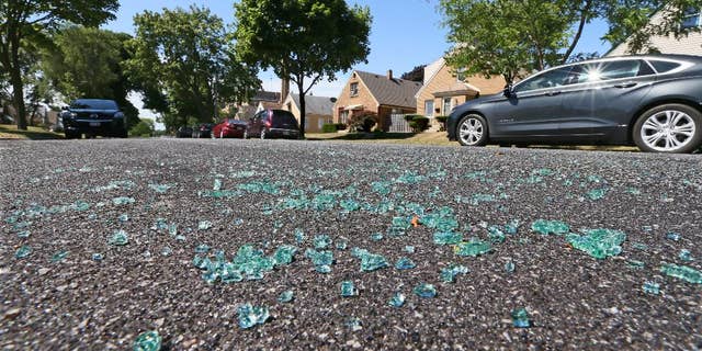 Broken auto glass is scattered in the street in the 3500 Blk. of S. 17th St. in Milwaukee, where a Milwaukee Police officer was shot while seated in the front seat of his squad car early Sunday, July 17, 2016. A domestic violence suspect opened fire on the officer, who was sitting in his squad car early Sunday, seriously wounding him before fleeing and apparently killing himself shortly afterward, authorities said. (Michael Sears/Milwaukee Journal Sentinel via AP)