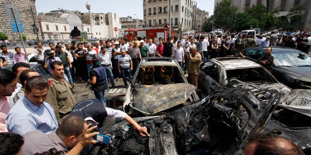 June 28, 2012: Syrians inspect burned cars at the site of a blast in the Syrian capital Damascus.