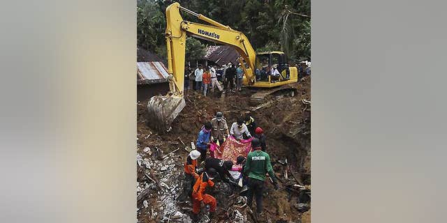 Oct. 4: Indonesian rescue volunteers cover a body before removing it from an area hit by landslides in the Sumatran Island village of Jumanak.