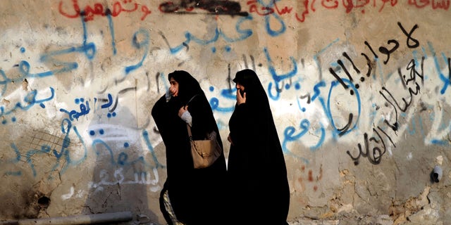 Bahraini women cover their mouths from tear gas during clashes between anti-government protester and riot police in Bani Jamra, Bahrain, Sunday, Feb. 24, 2013. Clashes erupted in villages nationwide with protesters demanding the release for burial of the body of Mahmoud Isa al-Jazeeri, 20, who died Thursday from injuries sustained during earlier clashes with police. Graffiti on the wall in Arabic reads, "no dialogue, down Hamad," referring to Bahrain's king. (AP Photo/Hasan Jamali)