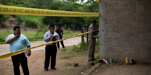 FILE - In this July 3, 2014 file photo, state authorities use crime scene tape to seal off an unfinished warehouse that was the site of a shootout between Mexican soldiers and alleged criminals on the outskirts of the village of San Pedro Limon in Mexico state, Mexico. Three soldiers have been charged with homicide in the June killings of 22 suspected gang members in southern Mexico, Attorney General Jesus Murillo Karam announced on Tuesday Sept. 30 2014. (AP Photo/Rebecca Blackwell, File)
