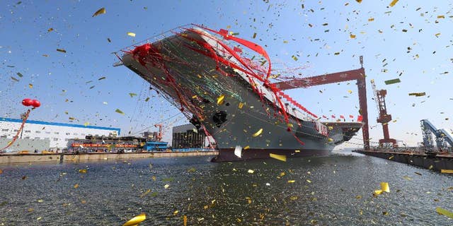 In this photo released by China's Xinhua News Agency, a newly-built aircraft carrier is transferred from dry dock into the water at a launch ceremony at a shipyard in Dalian in northeastern China's Liaoning Province, Wednesday, April 26, 2017. China launched its first aircraft carrier built entirely on its own on Wednesday, in a demonstration of the growing technical sophistication of its defense industries and determination to safeguard its maritime territorial claims and crucial trade routes. (Li Gang/Xinhua via AP)
