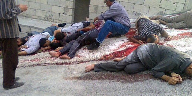 In this citizen journalism image released on Thursday, May 2, 2013 by a group that calls itself The Syrian Revolution Against Bashar Assad, which has been authenticated based on its contents and other AP reporting, a Syrian man, center, identifies dead bodies, who were killed according to activists by Syrian forces loyal to Bashar Assad, in Bayda village, in the mountains outside the coastal city of Banias, Syria. Syria's main opposition group on Friday accused President Bashar Assad's regime of committing a "large-scale massacre" in a Sunni village near the Mediterranean coast, killing scores of people, according to activists. (AP Photo/The Syrian Revolution Against Bashar Assad)