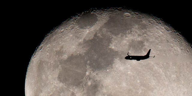 An airplane flies against the backdrop of the rising moon after taking off from Miami International airport, Sunday, Feb. 12, 2017, above Surfside, Fla. (AP Photo/Wilfredo Lee)