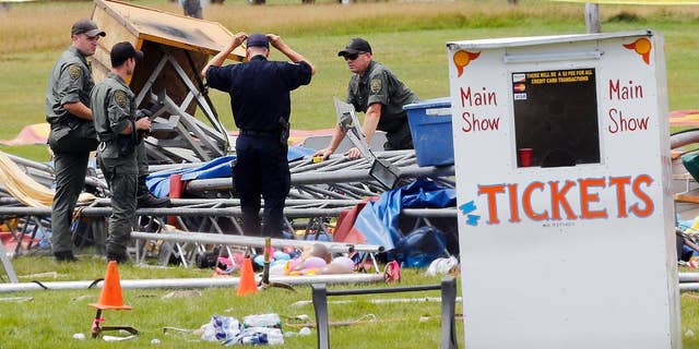 FILE - In this Aug. 4, 2015 file photo, investigators work at the scene of a circus tent that collapsed the previous day when a storm blew through, toppling it and killing a father and his 6-year-old daughter at the fairgrounds in Lancaster, N.H. In a plea agreement on Wednesday, May 3, 2017, a judge ordered the Florida-based circus operator to pay $15,000 in fines for operating without a license. (AP Photo/Jim Cole, File)