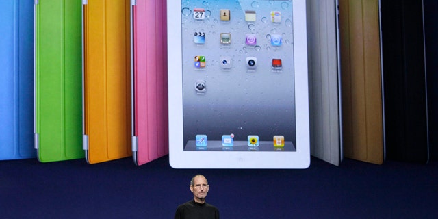 Apple chairman and CEO Steve Jobs stands under an image of the iPad 2 at an Apple event at the Yerba Buena Center for the Arts Theater in San Francisco, Wednesday, March 2, 2011.