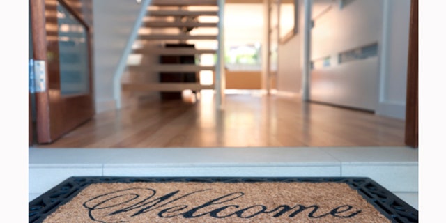 Close up of a welcome mat in front of an inviting house.