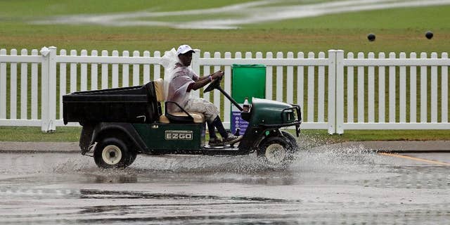 A worker drives a golf cart through standing water during a weather delay at the second round of the St. Jude Classic golf tournament Friday, June 6, 2014, in Memphis, Tenn. (AP Photo/Mark Humphrey)