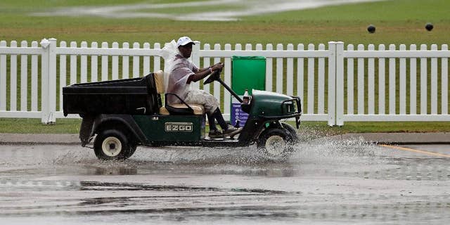 A worker drives a golf cart through standing water during a weather delay at the second round of the St. Jude Classic golf tournament Friday, June 6, 2014, in Memphis, Tenn. (AP Photo/Mark Humphrey)