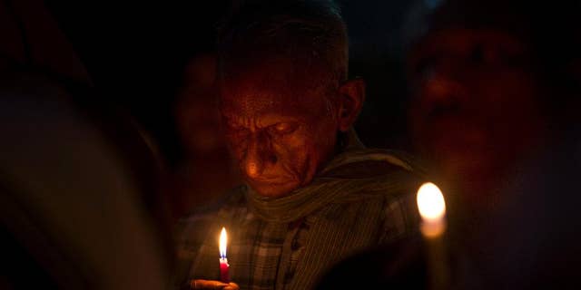 An Indian man prays as Christians and others hold a candle light vigil to condemn the gang rape of a nun at a Christian missionary school in eastern India outside the Sacred Heart cathedral in New Delhi, India, Monday, March 16, 2015. According to police a nun in her 70s was gang-raped by a group of bandits when she tried to prevent them from committing a robbery in the Convent of Jesus and Mary School in West Bengal state's Nadia district. The attack early Saturday is the latest crime to focus attention on the scourge of sexual violence in India. (AP Photo/Saurabh Das)