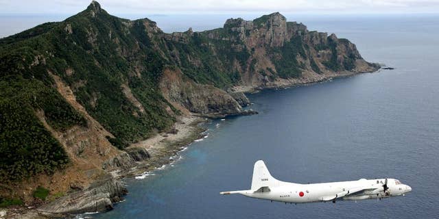 FILE - In this Oct. 13, 2011 file photo, Japan Maritime Self-Defense Force P-3C Orion surveillance plane flies over the disputed islands, called the Senkaku in Japan and Diaoyu in China, in the East China Sea. Japan protested to China on Thursday, June 9, 2016, after spotting a Chinese warship for the first time near disputed islands in the East China Sea. Japanese officials said a Chinese navy frigate was seen off the coast of the Japanese-controlled Senkaku islands, also claimed by China and called the Diaoyu islands. The ship did not violate Japan's territorial waters, and it has since left the area.(Kyodo News via AP, File) JAPAN OUT, CREDIT MANDATORY