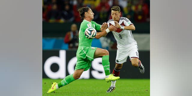 Algeria's Mehdi Mostefa, left, pushes off Germany's Mesut Ozil to stop his attack during the World Cup round of 16 soccer match between Germany and Algeria at the Estadio Beira-Rio in Porto Alegre, Brazil, Monday, June 30, 2014. (AP Photo/Kirsty Wigglesworth)