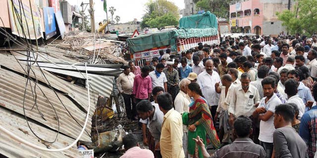 People stand at the site of an accident after a truck driver lost control and plowed into a group of protesting farmers in Yerpedu, in the southern Indian state of Andhra Pradesh, Friday, April 21, 2017. At least a dozen of those killed were electrocuted because the bus first hit an electricity pole causing high-tension wires to fall onto the crowd, police official Jaya Lakshmi said. The farmers were gathered outside the main police station protesting against illegal sand mining in their area. (AP Photo)