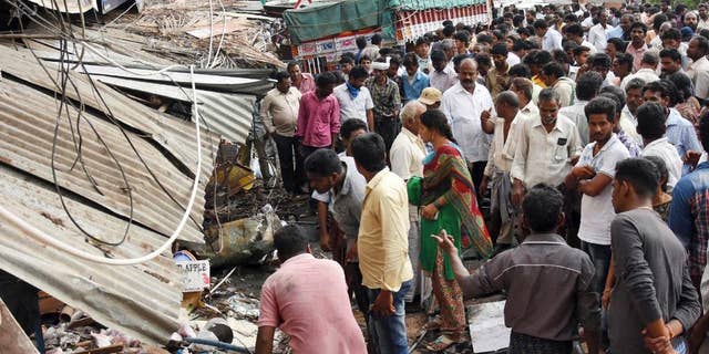 People stand at the site of an accident after a truck driver lost control and plowed into a group of protesting farmers in Yerpedu, in the southern Indian state of Andhra Pradesh, Friday, April 21, 2017. At least a dozen of those killed were electrocuted because the bus first hit an electricity pole causing high-tension wires to fall onto the crowd, police official Jaya Lakshmi said. The farmers were gathered outside the main police station protesting against illegal sand mining in their area. (AP Photo)