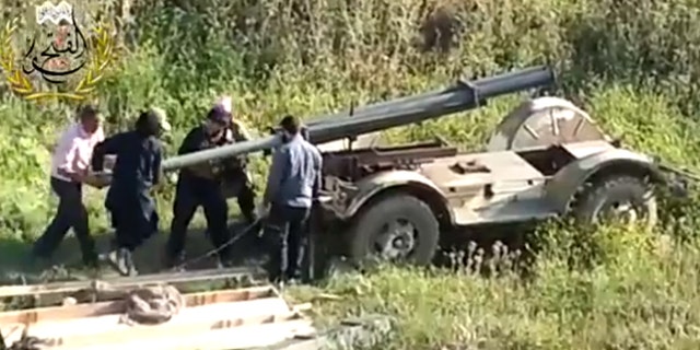 This image taken from video obtained from Ugarit News, which has been authenticated based on its contents and other AP reporting, shows Syrian rebels preparing to fire a rocket at Mannagh air base in Aleppo province, Syria, Monday, May 13, 2013. The Syrian government wants more details before deciding whether to take part in a proposed U.S.-Russian initiative to negotiate a peaceful end to Syria's crisis, the country's information minister said, staking out a similar position to the main opposition group.(AP Photo/Ugarit News via AP video)