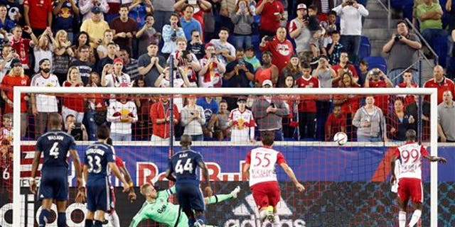 Vancouver Whitecaps FC goalkeeper David Ousted, center left, watches the ball after he deflected a penalty kick by New York Red Bulls forward Bradley Wright-Phillips, right, during the second half of an MLS soccer match, Saturday, June 20, 2015, in Harrison, N.J. Ousted denied Wright-Phillips on two penalty kicks and the Whitecaps won 2-1. (AP Photo/Julio Cortez)