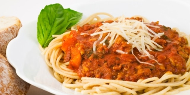 Bowl of whole wheat spaghetti and sauce. The sauce includes ground turkey, fresh basil, tomato sauce, bell peppers, onions, mushrooms, garlic, olive oil and italian seasonings.