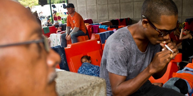 Cuban migrants sit outside the immigration office in Peñas Blancas, Costa Rica, Tuesday, Nov. 17, 2015. More than 1,000 Cuban migrants heading north to the United States tried to cross the border from Costa Rica into Nicaragua, causing tensions to soar between the neighbors as security forces sought to turn them back. Nicaragua's government responded furiously on Sunday with a statement saying that Costa Rica "had deliberately and irresponsibly thrown, and continues to throw" the Cuban migrants into its territory, violating its national sovereignty. (AP Photo/Esteban Felix)
