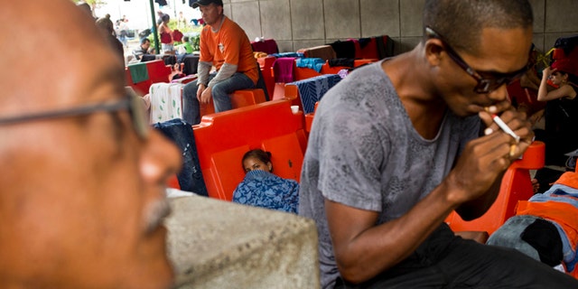 Cuban migrants sit outside the immigration office in Peñas Blancas, Costa Rica, Tuesday, Nov. 17, 2015. More than 1,000 Cuban migrants heading north to the United States tried to cross the border from Costa Rica into Nicaragua, causing tensions to soar between the neighbors as security forces sought to turn them back. Nicaragua's government responded furiously on Sunday with a statement saying that Costa Rica "had deliberately and irresponsibly thrown, and continues to throw" the Cuban migrants into its territory, violating its national sovereignty. (AP Photo/Esteban Felix)