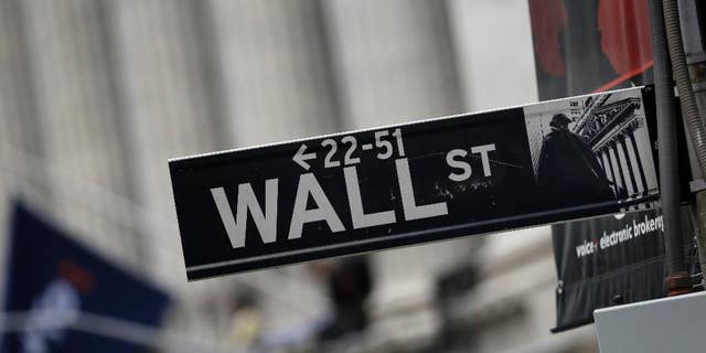 FILE - This Oct. 2, 2014 photo shows a Wall Street sign adjacent to the New York Stock Exchange, in New York. U.S. stocks are wavering in early trading more big companies turn in earnings reports. Markets in Asia surged on optimism over recent reforms in China, on Tuesday, April 21, 2015. (AP Photo/Richard Drew)