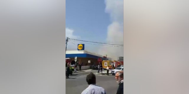 Smoke rises behind a supermarket near Lisbon after a small plane crashed. Portuguese officials say a small plane has crashed beside a supermarket near Lisbon, killing four people on board the aircraft and one on the ground. Four people were slightly injured. (Ramiro Ribeiro via AP)