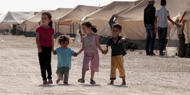 Syrian refugee children walk amid tents at the Zaatri refugee camp, near the Jordanian border with Syria, on September 11, 2012
