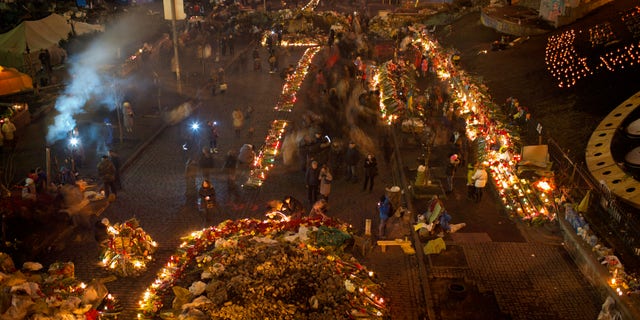 People light cantles and place flowers at a memorial for the people killed in clashes with the police at Kiev's Independence Square, the epicenter of the country's current unrest, Ukraine, Tuesday, Feb. 25, 2014. Parliament speaker says that a new government should be in place by Thursday, a delay reflecting intense ongoing consultations. Oleksandr Turchinov has previously said the new government could be formed on Tuesday. Turchinov was named Ukraine's interim leader after President Viktor Yanukovych fled the capital after signing a peace deal with opposition leaders to end violent clashes between police and protesters and Kiev. (AP Photo/Emilio Morenatti)