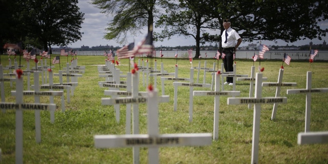 Bob Lewis looks over a field of crosses with names while participating in the College Point Memorial Day Parade in New York, Sunday, May 26, 2013. Lewis made the crosses, 137, for all the service members from College Point that were killed from the Civil War to the Vietnam War. (AP Photo/Seth Wenig)