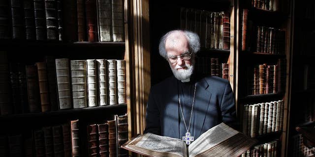 FILE - In this file photo dated Wednesday, May 25, 2011, then Archbishop of Canterbury Dr Rowan Williams poses with a 400-year old King James Bible at his London residence, Lambeth Palace.  According to a statement from the London Museum released Sunday April 16, 2017, the remains of five former archbishops of Canterbury were discovered during renovation works inside a secret tomb beneath a building located next to Lambeth Palace, including the remains of Richard Bancroft who became archbishop in 1604 and played a major role in production of the King James Bible. (AP Photo/Akira Suemori, FILE)