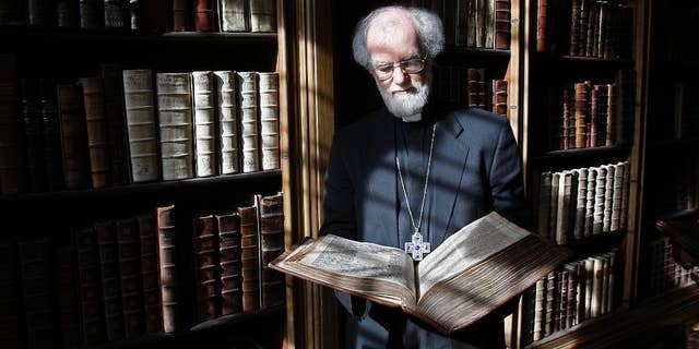 FILE - In this file photo dated Wednesday, May 25, 2011, then Archbishop of Canterbury Dr Rowan Williams poses with a 400-year old King James Bible at his London residence, Lambeth Palace. According to a statement from the London Museum released Sunday April 16, 2017, the remains of five former archbishops of Canterbury were discovered during renovation works inside a secret tomb beneath a building located next to Lambeth Palace, including the remains of Richard Bancroft who became archbishop in 1604 and played a major role in production of the King James Bible. (AP Photo/Akira Suemori, FILE)