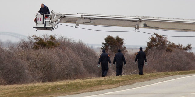 April 4, 2011: Police aided by a man in a fire department bucket ladder search in the brush near Oak Beach, N.Y. Three sets of human remains were found Monday, bringing to eight the total number of bodies found in the area since December.