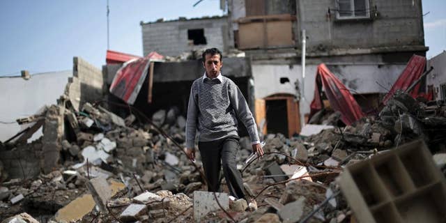 In this Monday, Nov. 17, 2014 photo, Mahmoud Abu Amer, 37, walks amid the ruins of an apartment building where 16 relatives were killed by an Israeli airstrike on July 29, in Khan Younis, Gaza. The building was one of scores targeted by Israel in its war last summer with the Islamic militant Hamas. Israel says it only attacked homes used by militants for military purposes, while Palestinians say warplanes often struck without regard for civilians. (AP Photo/Adel Hana)