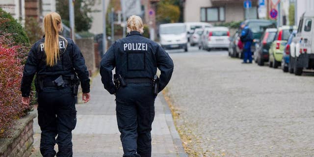 Policewomen  walk along  a street in Hameln, Germany, Monday Nov. 21, 2016. A woman was seriously injured when she was dragged Sunday through the streets of the northern German town behind a car with a cord tied around her neck. Her ex-partner later turned himself in to authorities, prosecutors said Monday,  (Julian Stratenschulte/dpa via AP)