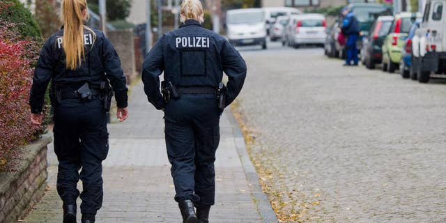 Policewomen walk along a street in Hameln, Germany, Monday Nov. 21, 2016. A woman was seriously injured when she was dragged Sunday through the streets of the northern German town behind a car with a cord tied around her neck. Her ex-partner later turned himself in to authorities, prosecutors said Monday, (Julian Stratenschulte/dpa via AP)