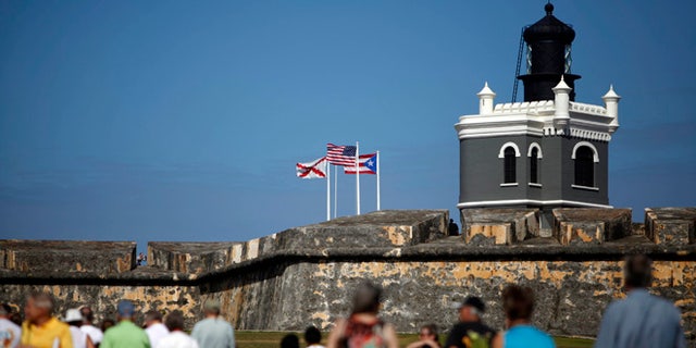 Tourists walk near the 16th century Spanish fort called El Morro in Old San Juan, Puerto Rico, Jan. 24, 2013. There's an entrance fee to enter the Castillo San Felipe del Morro, but the best way to enjoy this U.S. National Historic Site requires no money at all. The fort that towers over San Juan Bay, known universally as just âEl Morro,â is a great place to stroll, especially at sunset. The massive rolling expanse of grass at the foot of the fort has spectacular views in any direction. It's a popular place to picnic and fly a kite, sold by nearby street vendors.(AP Photo/Ricardo Arduengo)
