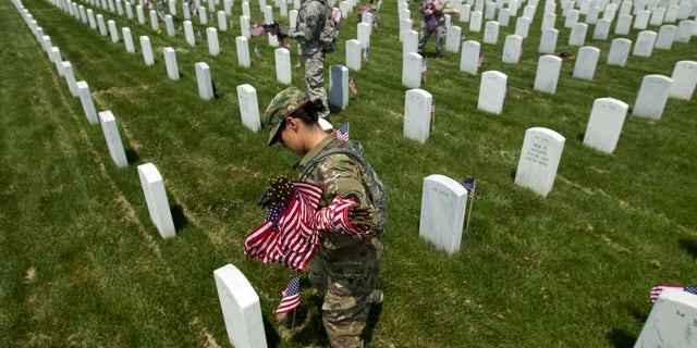 Members of the Old Guard with the Washington Memorial in the back, place flags in front of every headstone at Arlington National Cemetery in Arlington, Va., Thursday, May 26, 2016. Soldiers were to place nearly a quarter of a million American flags at the cemetery as part of a Memorial Day tradition. ( AP Photo/Jose Luis Magana)