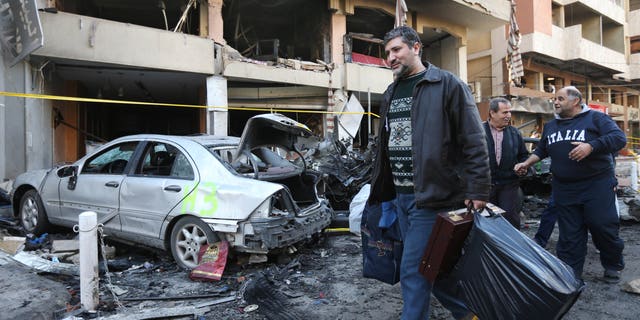 A Lebanese man carries his belongings as he leaves his damaged house at the site of an explosion in a stronghold of the Lebanese Shiite group Hezbollah in Beirut, Lebanon, Friday, Jan. 3, 2014. An explosion tore through a crowded commercial street Thursday in a south Beirut neighborhood that is bastion of support for the Shiite group Hezbollah, killing several people, setting cars ablaze and sending a column of black smoke above the Beirut skyline. (AP Photo/Hussein Malla)