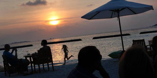 FILE - In this Feb. 16, 2012, file photo, foreign tourists gather at a sand-bar to watch sunset at Kurumba resort in Male atoll, Maldives. Maldives, best known for its palm-fringed beaches and luxury resorts, but riven by political power struggles since becoming a democracy only seven years ago. An explosion in September 2015 aboard the presidential boat set the Maldives on course for its latest political shakeup, with the Vice President Ahmed Adeeb arrested over the weekend on suspicion of high treason for allegedly plotting to assassinate the country’s leader. (AP Photo/Gemunu Amarasinghe, File)