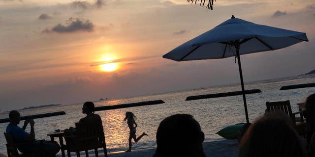 FILE - In this Feb. 16, 2012, file photo, foreign tourists gather at a sand-bar to watch sunset at Kurumba resort in Male atoll, Maldives. Maldives, best known for its palm-fringed beaches and luxury resorts, but riven by political power struggles since becoming a democracy only seven years ago. An explosion in September 2015 aboard the presidential boat set the Maldives on course for its latest political shakeup, with the Vice President Ahmed Adeeb arrested over the weekend on suspicion of high treason for allegedly plotting to assassinate the country’s leader. (AP Photo/Gemunu Amarasinghe, File)