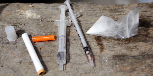 A bag of heroin and drug paraphernalia are seen at an abandoned house.