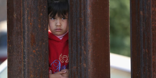 NOGALES, AZ - APRIL 01: A child on the Mexican side of the U.S.-Mexico border fence looks into Arizona during a special 'Mass on the Border' on April 1, 2014 in Nogales, Arizona. Catholic bishops led by the Archbishop of Boston Cardinal Sean O'Malley held the mass at the border fence to pray for comprehensive immigration reform and for those who have died along the border. (Photo by John Moore/Getty Images)