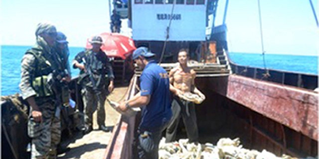 April 10, 2012: In this photo released by the Philippine Navy, Filipino naval personnel look at giant clam shells on board a Chinese fishing vessel at the disputed Scarborough Shoal in the South China Sea, near the Philippines.