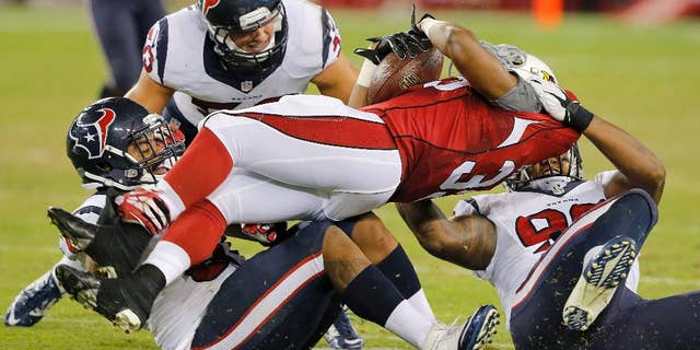 Arizona Cardinals running back Zach Bauman, center, is tackled by Houston Texans' Keith Browner, right, Max Bullough, rear, and Bronson Irwin, left, during the second half of an NFL preseason football game, Saturday, Aug. 9, 2014, in Glendale, Ariz. The Cardinals won 32-0. (AP Photo/Rick Scuteri)