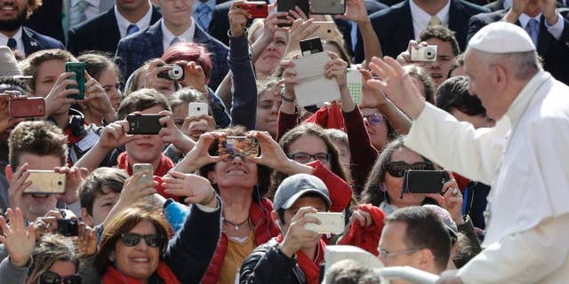 Faithful take snapshots of Pope Francis as he arrives for his weekly general audience in St. Peter square at the Vatican, Wednesday, April 26, 2017. (AP Photo/Andrew Medichini)