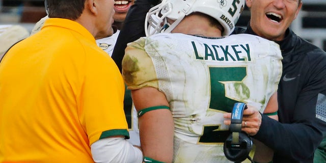 Baylor linebacker Eddie Lackey (5) gets a hug from head coach Art Briles, right, and defensive coordinator Phil Bennett, left, after returning an interception for a touchdown in the third quarter of a 41-38 win over TCU in an NCAA college football game in Fort Worth, Texas, Saturday, Nov. 30, 2013. (AP Photo/Dallas Morning News, Louis DeLuca) MANDATORY CREDIT; NO SALES; MAGAZINES OUT; TV OUT; INTERNET USE BY AP MEMBERS ONLY