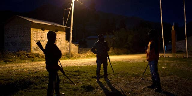 FILE - In this Nov. 25, 2015 file photo, members of a citizen's self-defense force stand guard in front of the health center where forensic anthropologists prepare the coffins with the exhumed remains of 34 people slain in 1992 by Shining Path guerrillas, in Valle Esmeralda de Huayao, Peru. The U.S. government sanctioned three leaders of Peru’s Shining Path guerrilla movement Tuesday, Nov. 22, 2016, whom it says “actively engaged in terrorism” as part of their mission to overthrow the Peruvian government. (AP Photo/Rodrigo Abd, File)