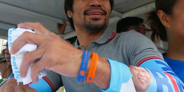 FILE - In this Friday, May 6, 2016, file photo, Congressman Manny Pacquiao, who is running for senator in the national elections, smiles from a campaign vehicle during a campaign rally in Navotas,north of Manila, Philippines. The boxing great appears to have won a seat in the Philippine Senate, according to unofficial results. Pacquiao has garnered more than 15 million votes, with about 93 percent of precincts reporting Tuesday, May 10, 2016. (AP Photo/Bullit Marquez, File)